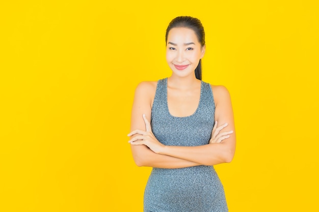 Porträt schöne junge asiatische Frau mit Sportbekleidung bereit für Übung auf gelber Wand