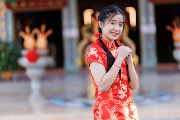 Porträt schöne süße Lächeln asiatische junge Frau trägt rotes Cheongsam-Kleid mit traditioneller Dekoration