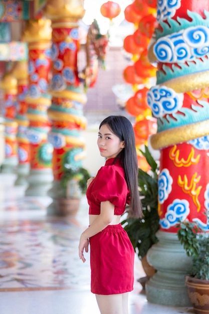 Porträt schönes Lächeln Asiatische junge Frau mit rotem Cheongsam-Kleid traditionelle Dekoration für das chinesische Neujahrsfest feiern die Kultur Chinas am chinesischen Schrein Öffentliche Orte in Thailand