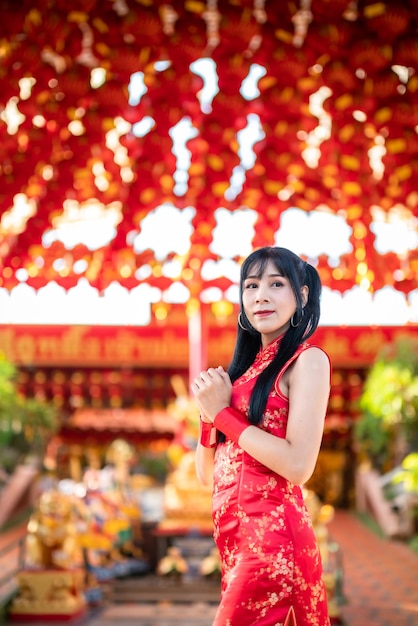 Porträt schönes Lächeln Asiatische junge Frau mit rotem Cheongsam-Kleid traditionelle Dekoration für das chinesische Neujahrsfest feiern die Kultur Chinas am chinesischen Schrein Öffentliche Plätze in Thailand