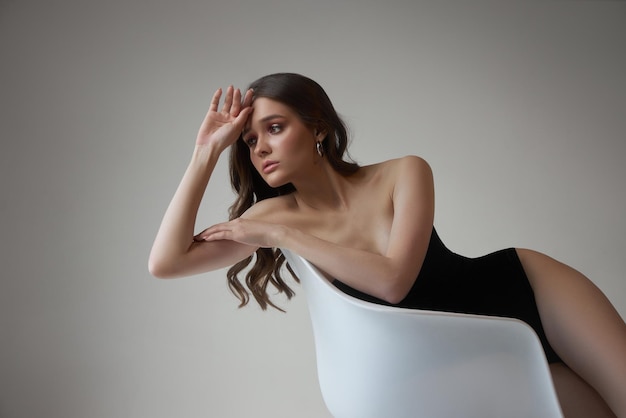 Porträt sexy Frau im schwarzen Bodysuit Studioporträt Perfekte Körperfigur einer jungen Frau mit langen lockigen Haaren