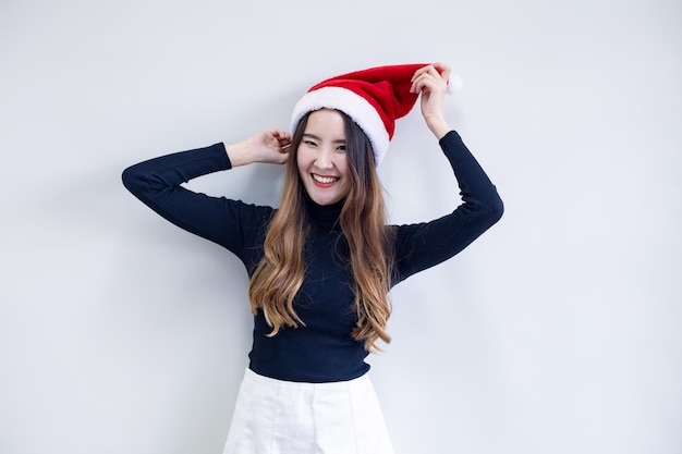 Porträt süße asiatische junge Frau im Kostüm Weihnachten und roten Weihnachtsmann-Hut mit Lächeln auf weißem Hintergrund und Kopie Raum tragen. Glücklich von der jugendlich Frau im Thema Weihnachten.
