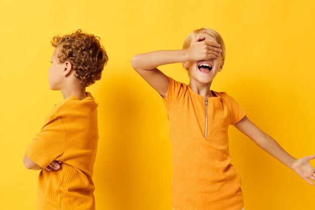 Porträt süßer Kinder in gelben T-Shirts, die nebeneinander stehen. Kindheitsgefühle gelber Hintergrund unverändert. Foto in hoher Qualität