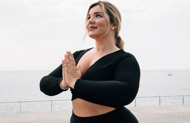 Porträt über ein Plus-Size-Mädchen, das an einem Sommertag Yoga vor dem Ozean praktiziert