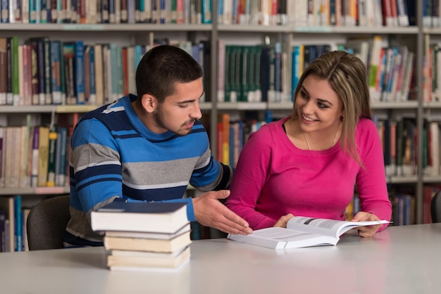 Porträt von cleveren Studenten mit offenem Buch, das es in der College-Bibliothek mit geringer Schärfentiefe liest