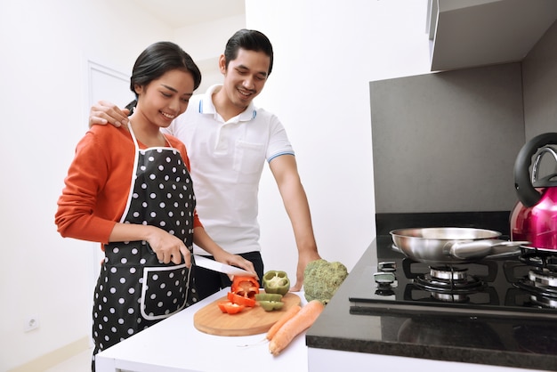 Porträt von den asiatischen Paaren, die zusammen lächeln und kochen