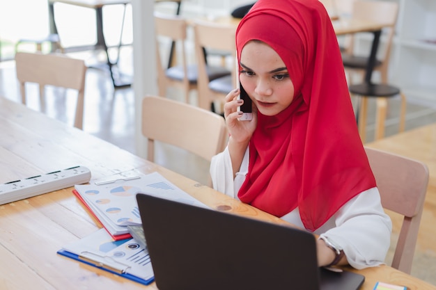 Porträt von den jungen moslemischen Geschäftsleuten, die rotes hijab, arbeitend im Café tragen.