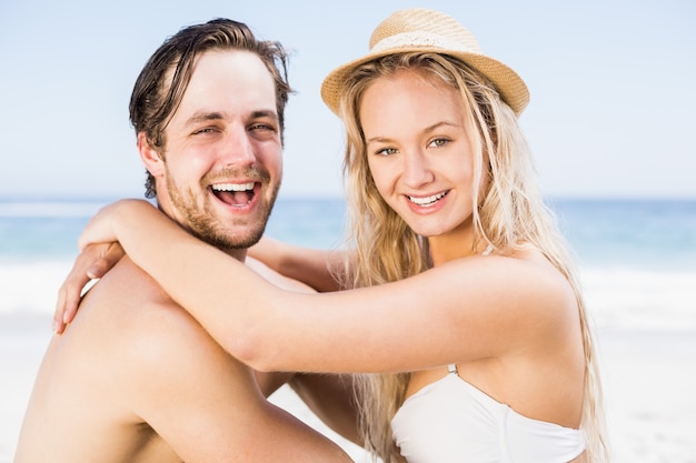 Porträt von den jungen Paaren, die zusammen auf dem Strand sitzen