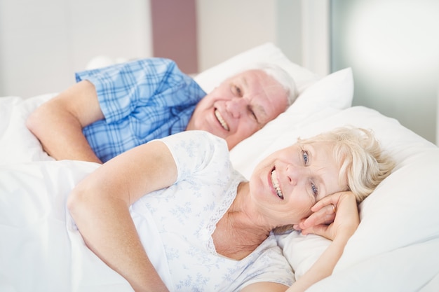 Porträt von den lächelnden älteren Paaren, die auf Bett sich entspannen