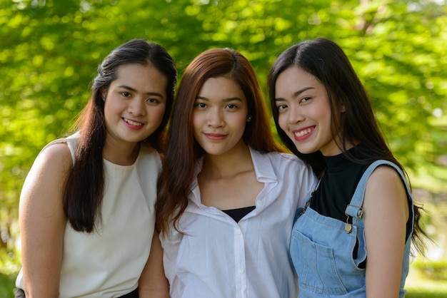 Porträt von drei jungen asiatischen Frauen als Freunde, die zusammen im Park draußen entspannen