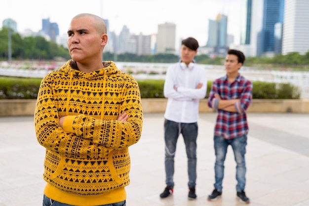 Porträt von drei jungen asiatischen Männern, die zusammen am Park in Bangkok, Thailand entspannen