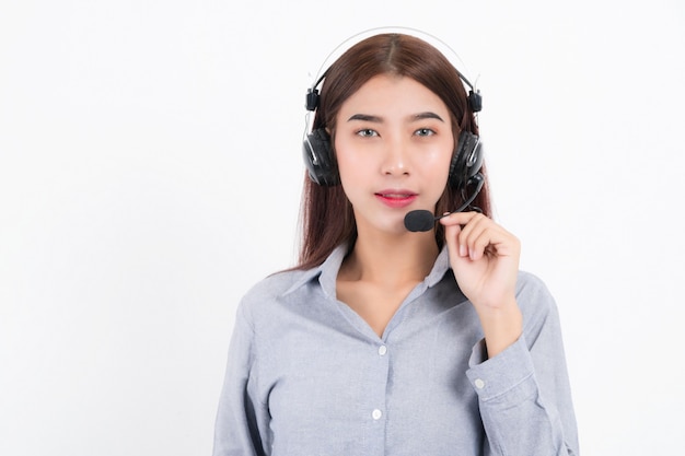 Porträt von glücklich lächelnden weiblichen Kundensupport-Telefonistin kurzes Haar, ein weißes Hemd mit Headset tragend, das auf einer Seite steht und den Kopfhörer isoliert auf weißem Hintergrund hält.