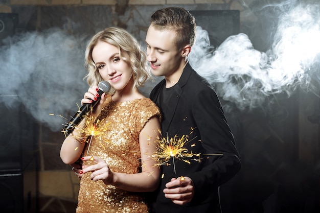 Porträt von glücklichen jungen Paaren mit Wunderkerzen singend mit Mikrofon.