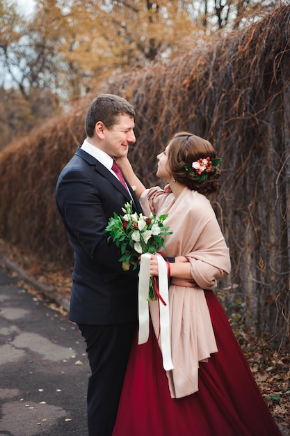 Porträt von glücklichen Jungvermählten in der Herbstnatur. Glückliche Braut und Bräutigam umarmen und küssen