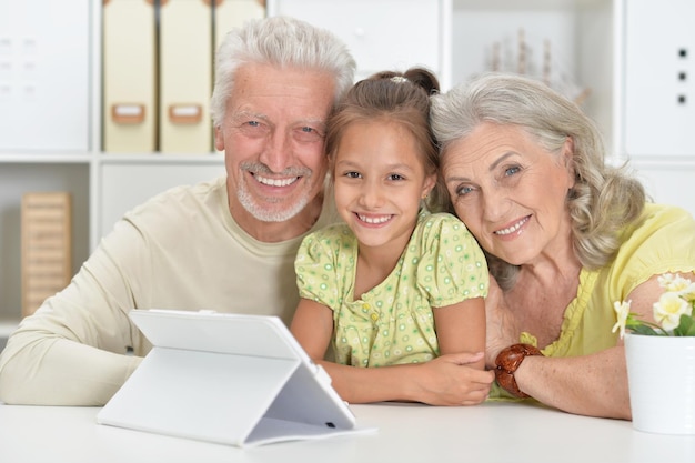 Porträt von Großeltern mit ihrer Enkelin mit Laptop zu Hause