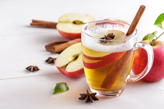 Porträt von hartem Apfelwein mit Zimtstange auf weißem Holztisch