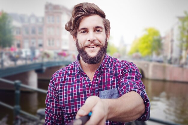 Porträt von Hipster mit Selfie-Stick gegen Kanal in Amsterdam?