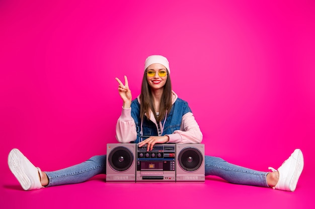 Porträt von ihr sie schöne attraktive schöne fröhliche fröhliche fröhliche Mädchen sitzen neben Boom-Box zeigt V-Zeichen Schnur isoliert auf hellen lebendigen Glanz lebendige rosa Fuchsia Farbe