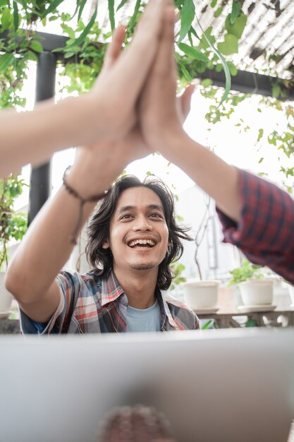 Porträt von jungen asiatischen studenten, die sich in einem café treffen, das zusammen high five macht