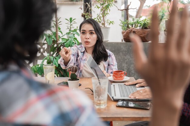 Porträt von jungen asiatischen Studenten, die sich in einem Café treffen. verärgert über ihren männlichen Freund und zeigte auf ihn