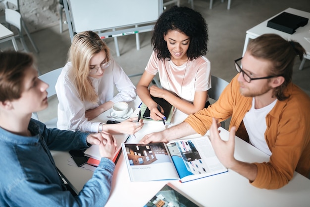 Porträt von jungen Leuten, die im Büro sitzen und etwas besprechen. Gruppe cooler Jungs, die an einem neuen Projekt arbeiten, während sie im Café sitzen