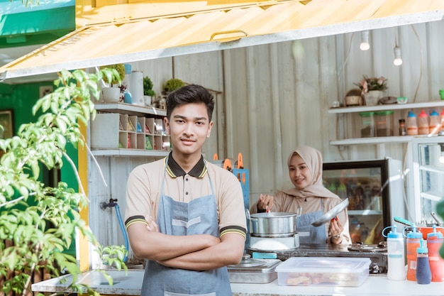 Porträt von jungen muslimischen Männern und Frauen, die Essen und Getränke unter Verwendung des Behälters verkaufen