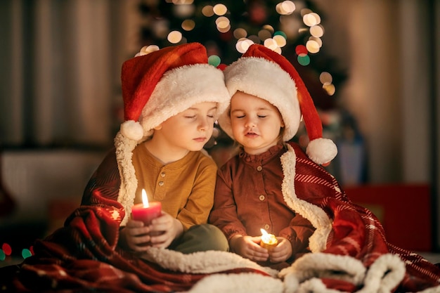 Porträt von Kindern, die an Heiligabend zu Hause sitzen und Wünsche aussprechen und beten