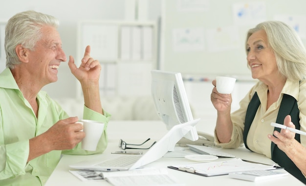 Porträt von leitenden Geschäftsleuten, die im Büro arbeiten und am Tisch sitzen