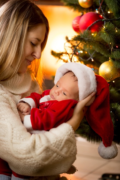 Porträt von Mutter und Baby im Weihnachtsmannkostüm am Kamin