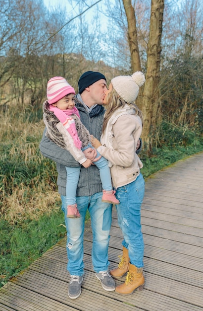 Porträt von Paaren mit ihrem glücklichen kleinen Tochterküssen. Familienliebeskonzept.