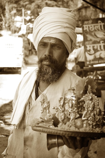 Foto porträt von sadhu, der religiöse skulpturen auf einem teller hält