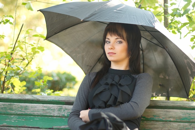 Porträt von schön mit Regenschirm im Park sitzend