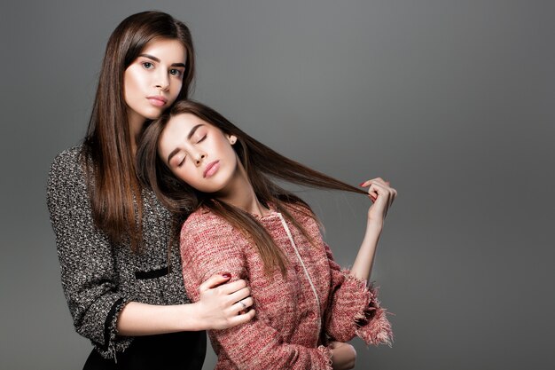 Porträt von schönen Zwillingsfrauen mit natürlichem Make-up und langen Haaren. Mode