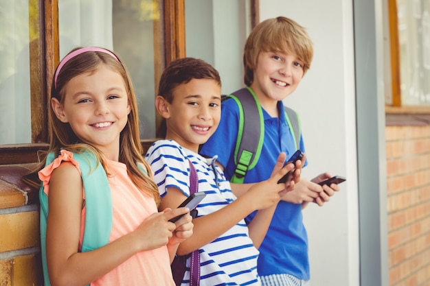 Porträt von Schulkindern, die Handy im Korridor verwenden