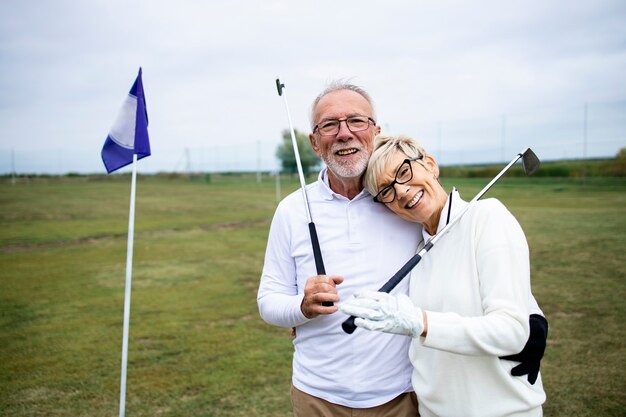 Porträt von Senioren oder Golfern, die ihren Ruhestand auf dem Golfplatz genießen.