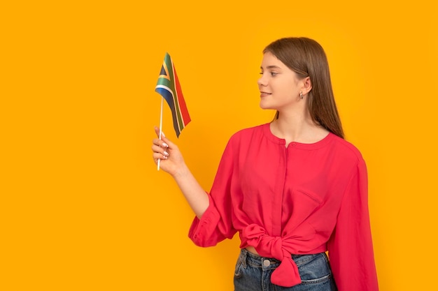 Porträt von Teenager-Mädchen mit Flagge von Südafrika auf einem orangefarbenen Hintergrund Studieren und Reisen in Südafrika