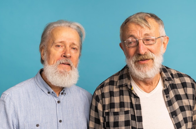Porträt von zwei älteren Mannfreunden, die über blauem Hintergrund stehen Freundschaft im Alter von und Senioren