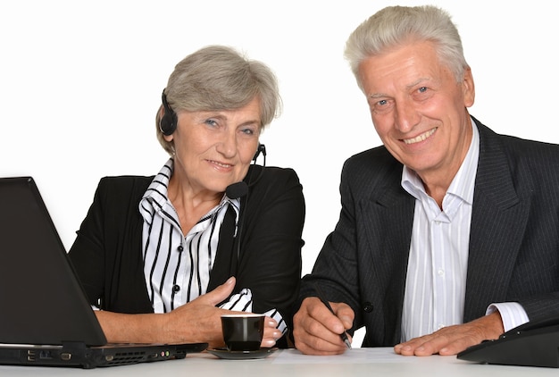 Porträt von zwei älteren Menschen, die mit einem Laptop auf weißem Hintergrund arbeiten