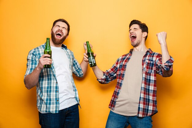 Porträt von zwei fröhlichen jungen männern, die bierflaschen halten