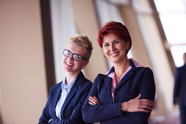 Porträt von zwei Geschäftsfrauen im modernen hellen Büroinnenraum, die in der Gruppe als Team stehen