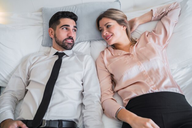 Porträt von zwei Geschäftsleuten, die eine Pause von der Arbeit machen und im Hotelzimmer auf dem Bett liegen. Geschäftsreisekonzept.