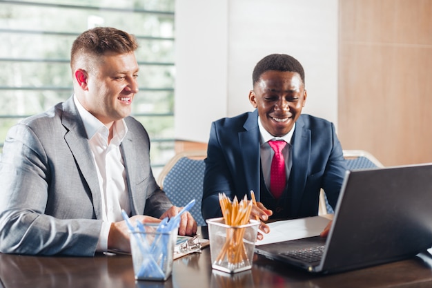 Porträt von zwei Geschäftspartnern, die zusammen an einem Tisch sitzen und arbeiten.