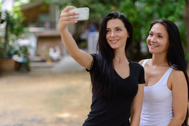 Porträt von zwei glücklichen schönen Frauen, die Selfie zusammen im Freien nehmen