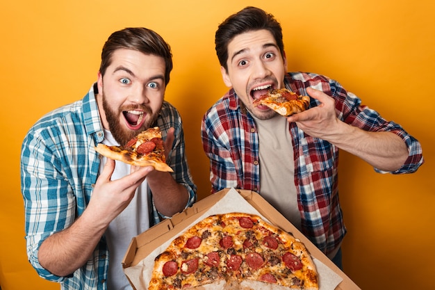 Porträt von zwei hungrigen jungen Männern, die Pizza essen