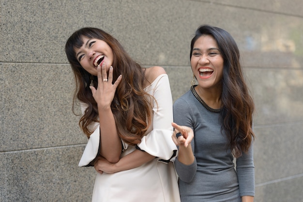 Porträt von zwei jungen asiatischen Geschäftsfrauen zusammen in der Stadt im Freien