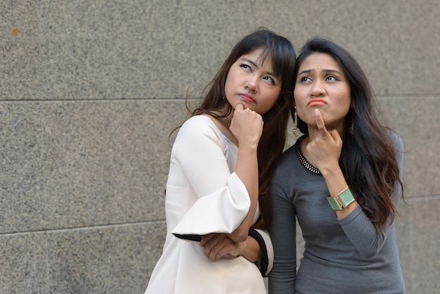 Porträt von zwei jungen asiatischen Geschäftsfrauen zusammen in der Stadt im Freien