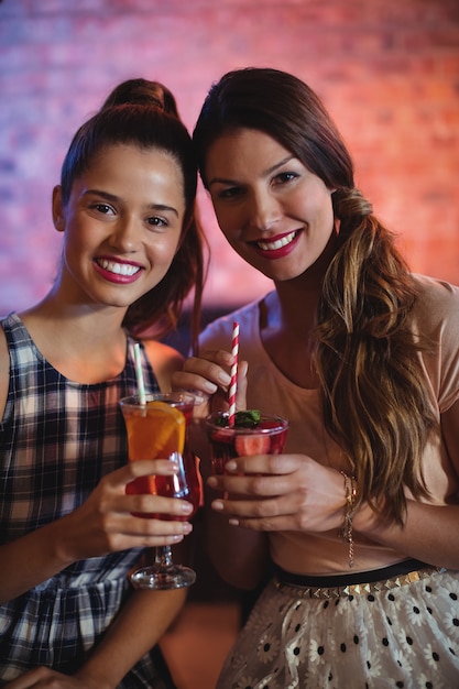 Porträt von zwei jungen Frauen, die Cocktailgetränke haben