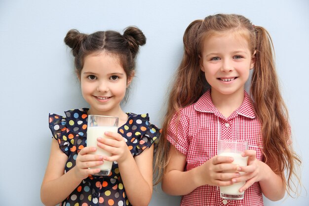 Porträt von zwei kleinen Mädchen mit Gläsern Milch auf Blau