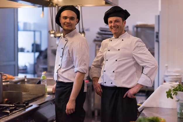 Porträt von zwei Köchen, die in der gewerblichen Küche im Restaurant zusammenstehen