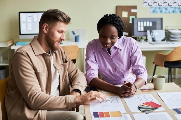 Porträt von zwei lächelnden Designern, die Farbmuster auswählen, während sie im Büro an einem UX-Projekt arbeiten